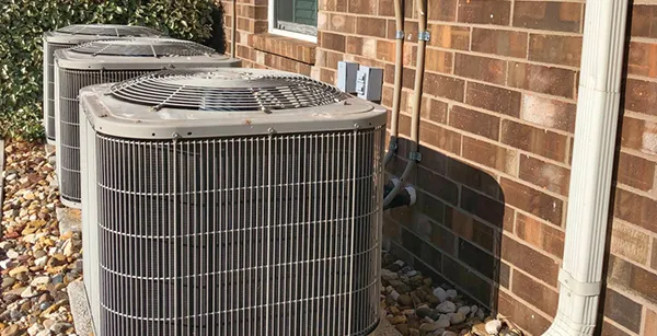 Outdoor AC units installed beside a brick wall for reliable home cooling
